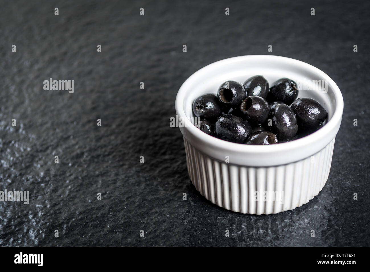 Olives noires sur table en pierre noire humide Banque D'Images