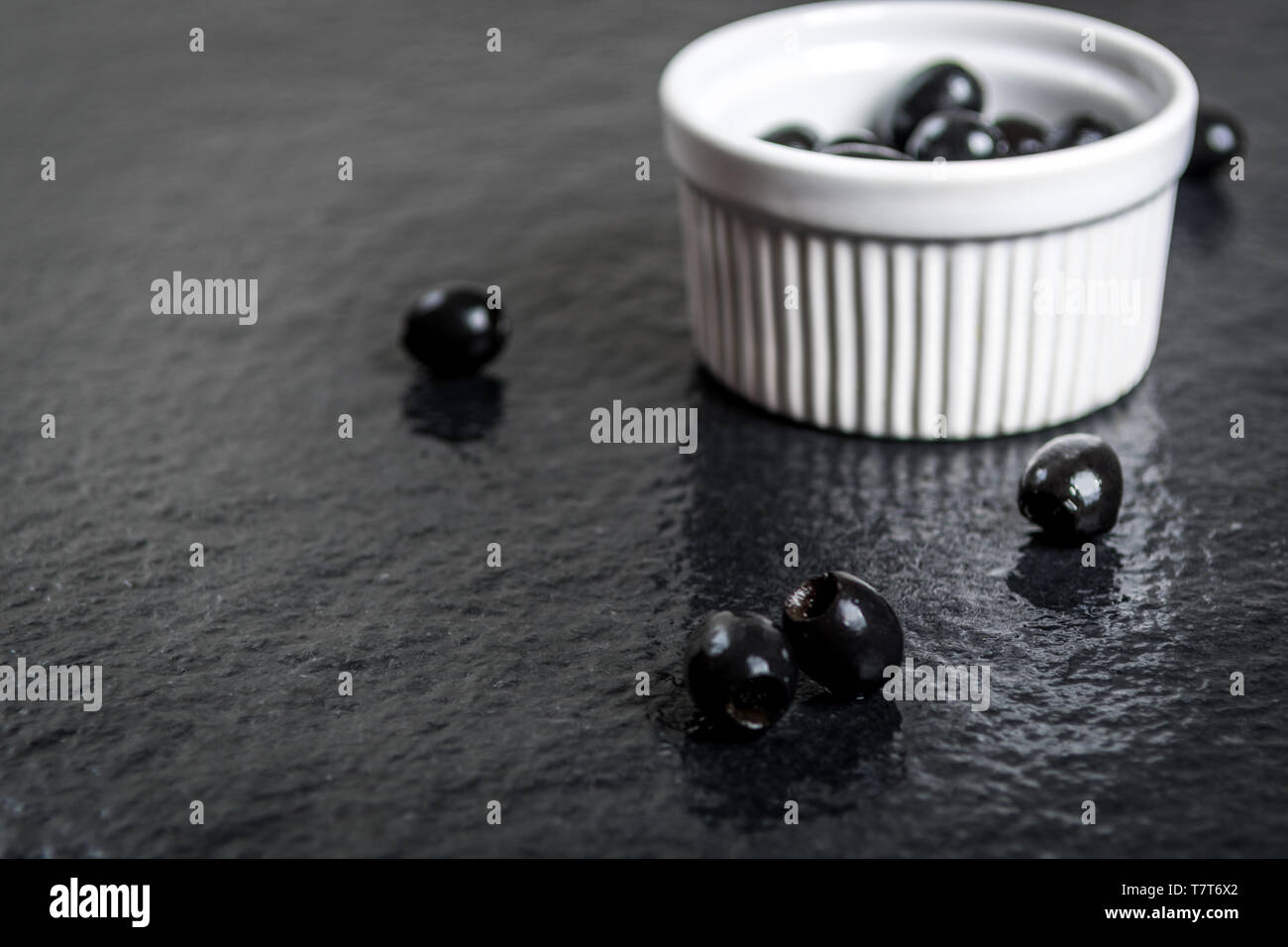 Olives noires sur table en pierre noire humide Banque D'Images