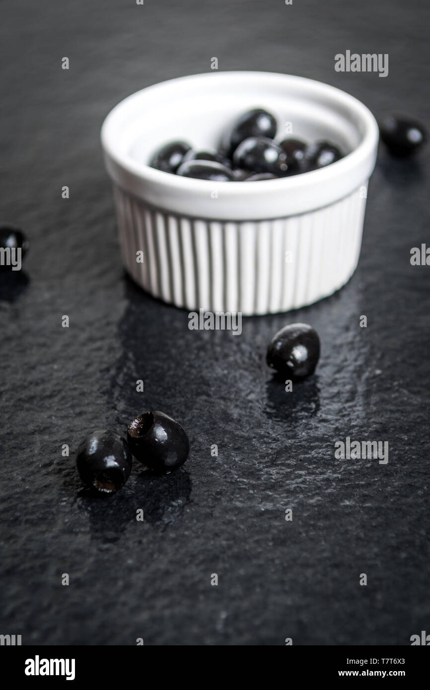 Olives noires sur table en pierre noire humide Banque D'Images