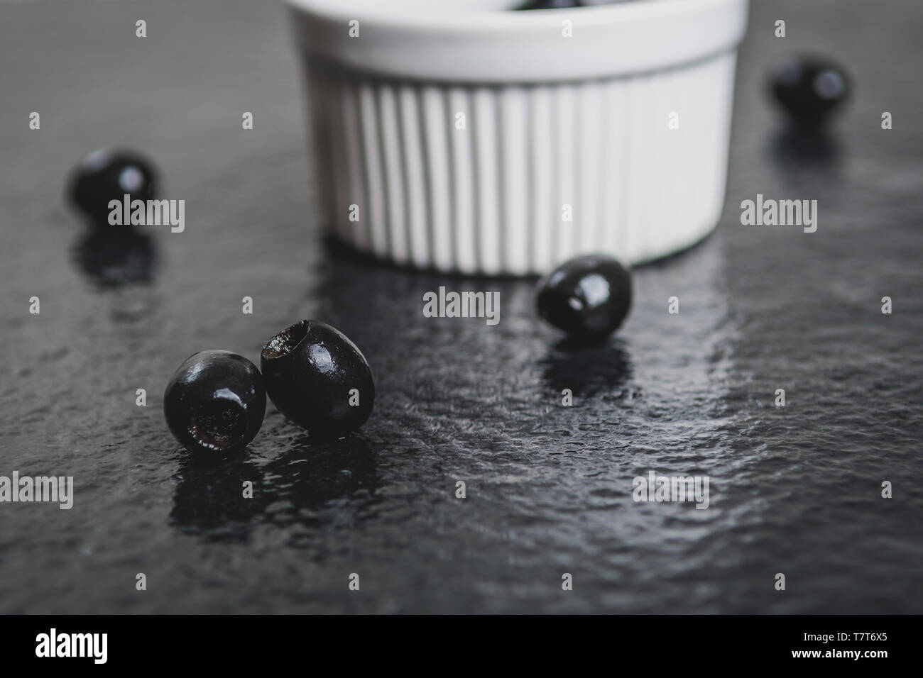 Olives noires sur table en pierre noire humide Banque D'Images