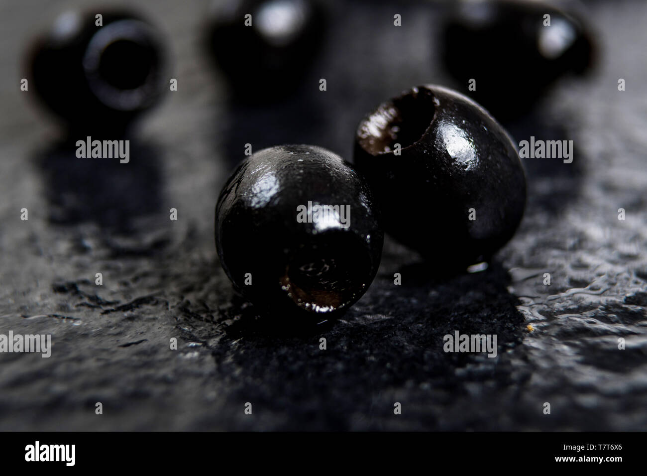 Olives noires sur table en pierre noire humide Banque D'Images