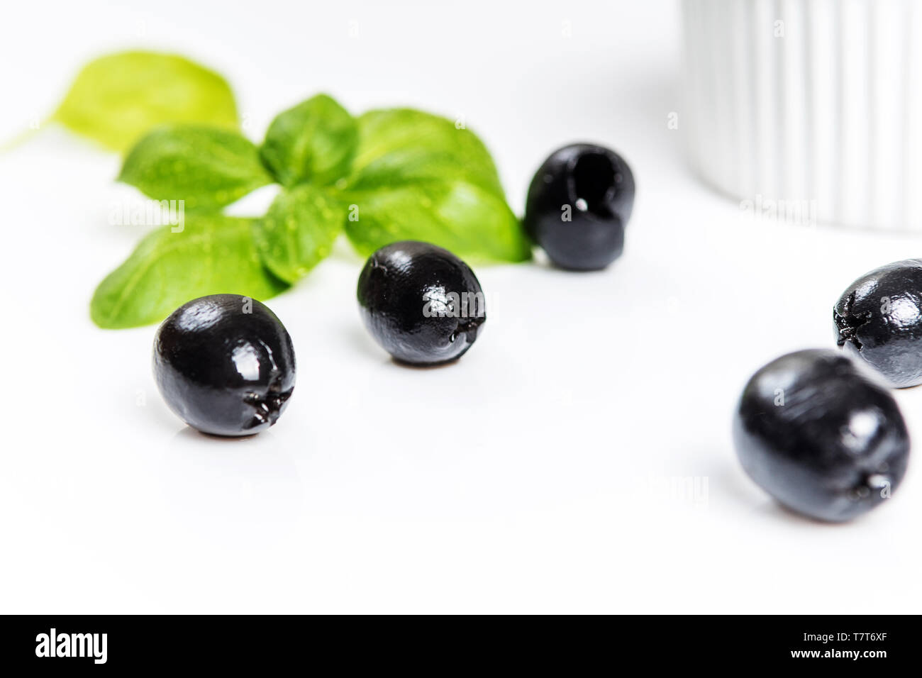 Les feuilles de basilic et olives noires sur fond blanc Banque D'Images