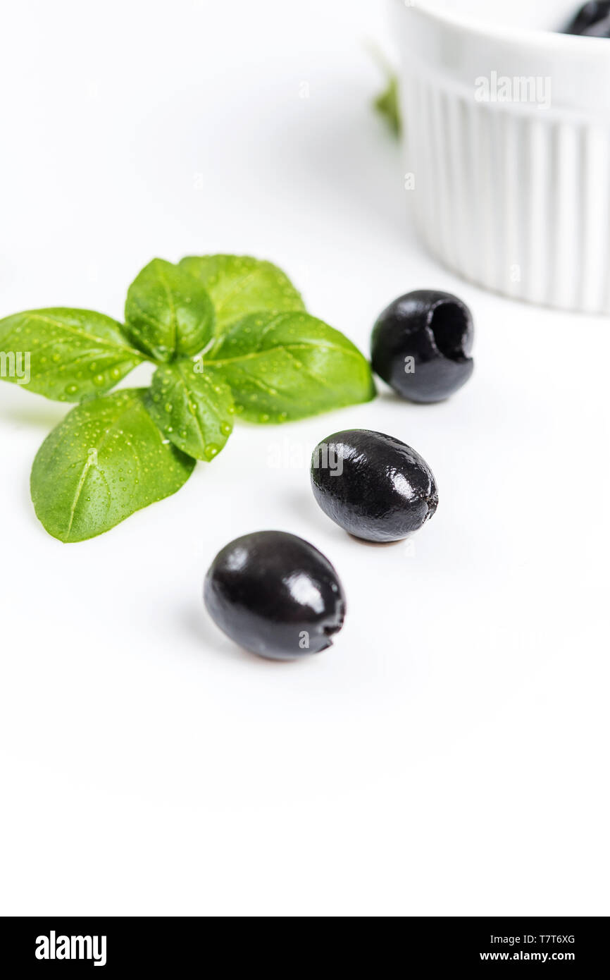 Les feuilles de basilic et olives noires sur fond blanc Banque D'Images
