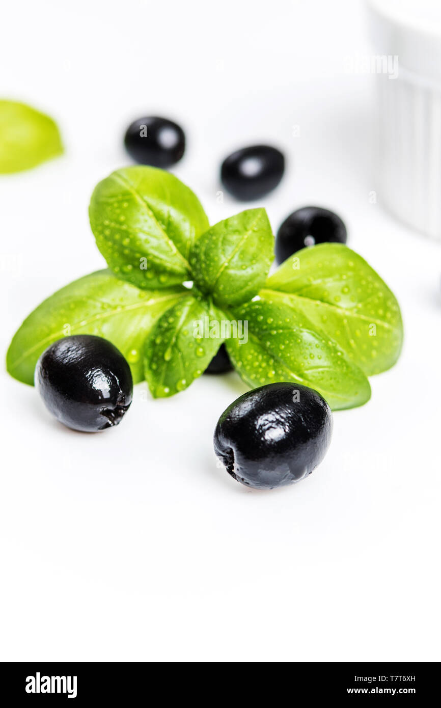 Les feuilles de basilic et olives noires sur fond blanc Banque D'Images