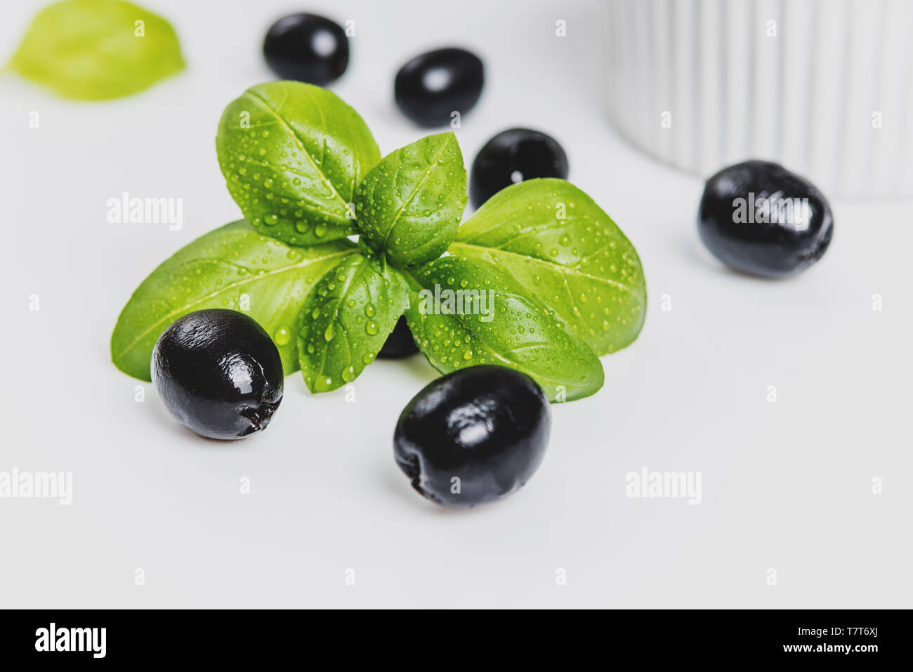 Les feuilles de basilic et olives noires sur fond blanc Banque D'Images