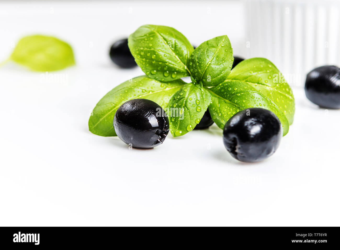 Les feuilles de basilic et olives noires sur fond blanc Banque D'Images