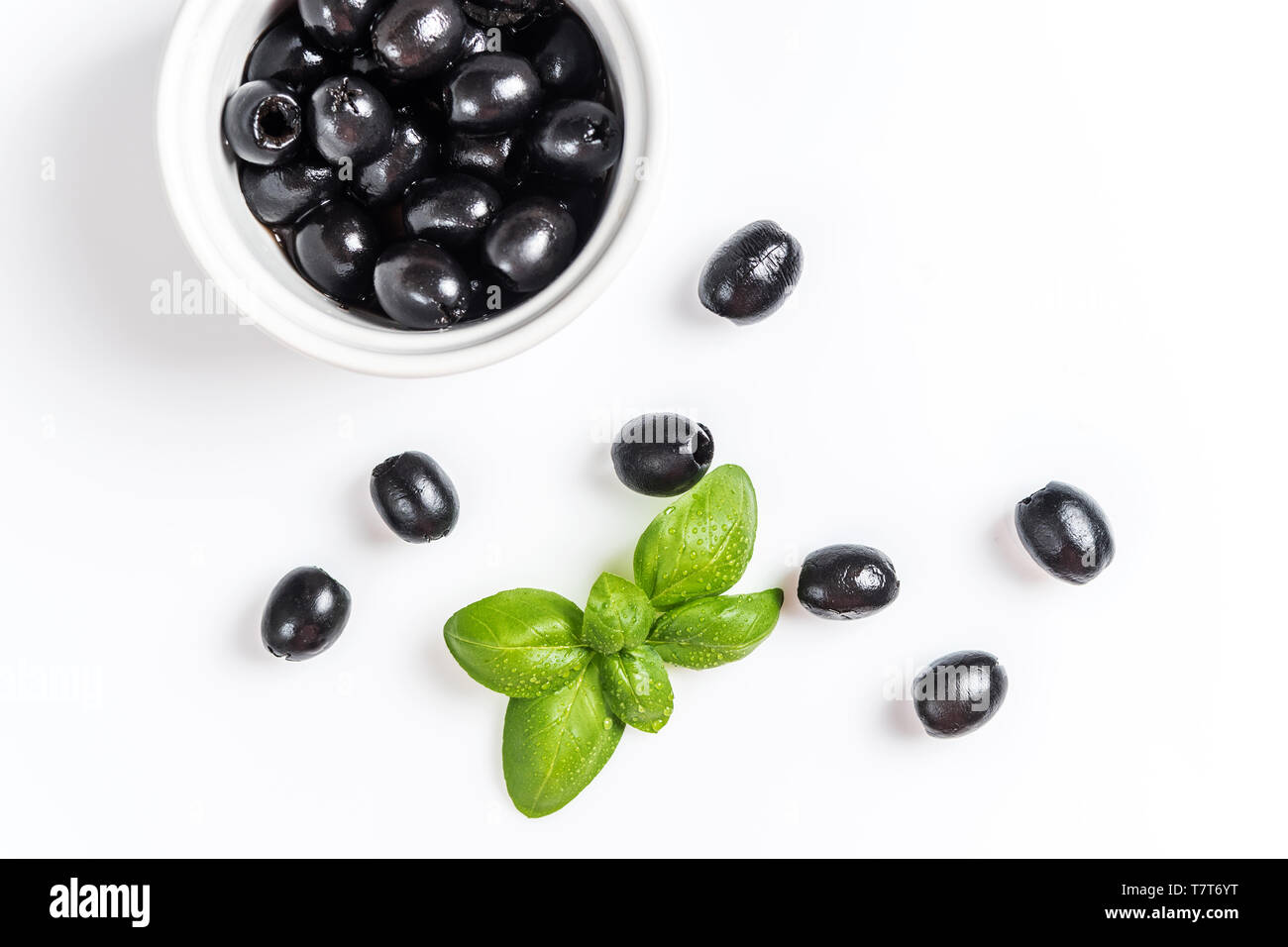 Les feuilles de basilic et olives noires sur fond blanc Banque D'Images