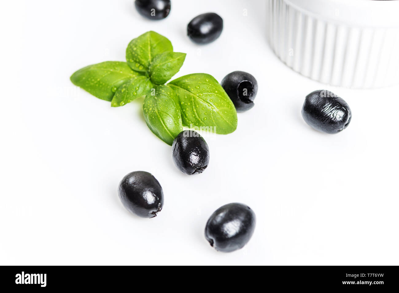 Les feuilles de basilic et olives noires sur fond blanc Banque D'Images