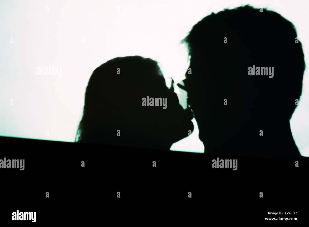 Résumé Contexte Les ombres de personnes homme et femme s'embrasser sur mur numérique à partir de la lumière du projecteur de cinéma sur un mur d'images noir et blanc Banque D'Images