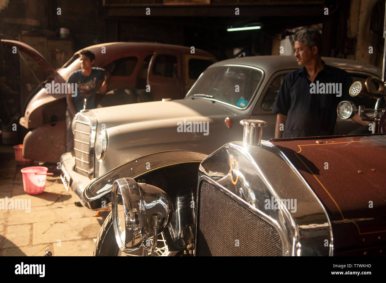 Stand de mécanique entre les voitures en cours de restauration, y compris une cinquantaine Mercedes Benz, dans un garage de l'atelier à Mumbai, Inde Banque D'Images