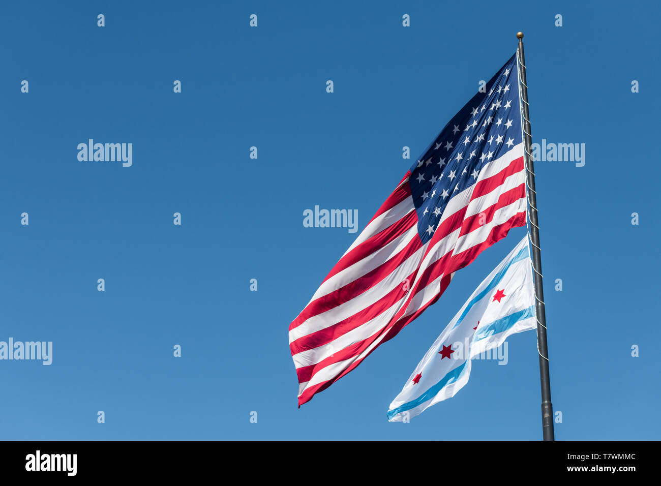 Le drapeau de la ville de Chicago et le drapeau américain dans le vent à Chicago contre ciel bleu clair Banque D'Images