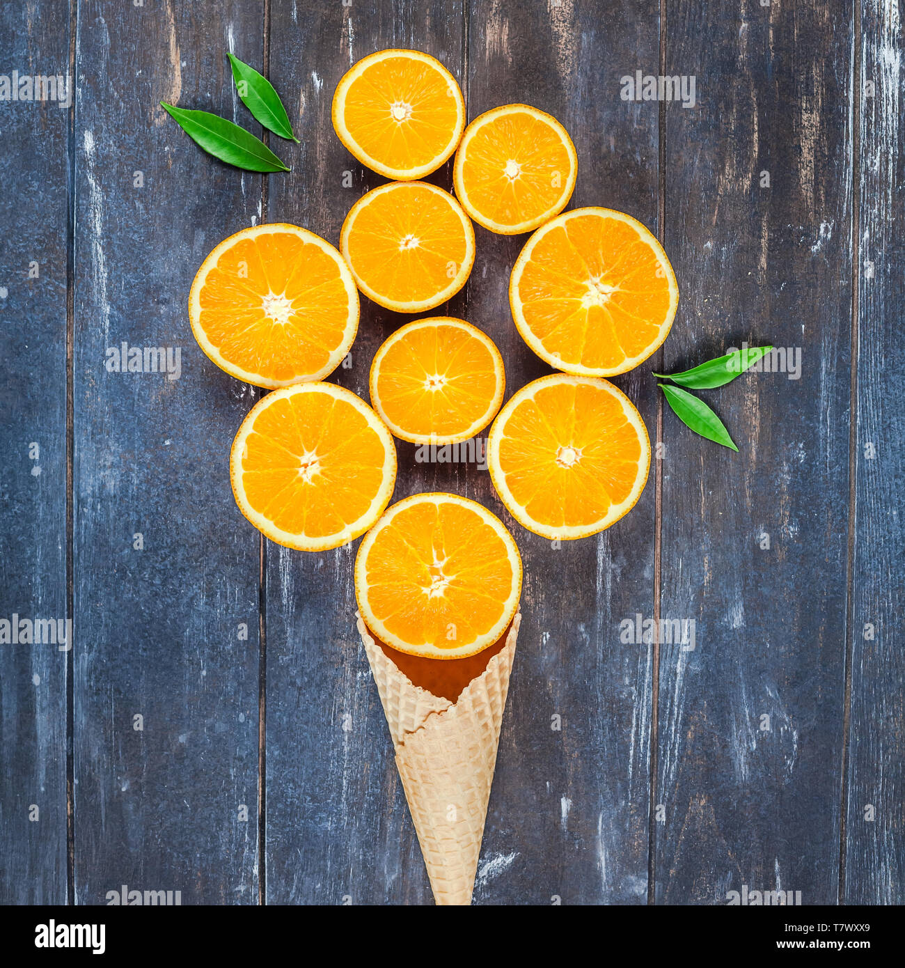 Plat à l'obscurité créative jeter Vue de dessus des tranches de fruits d'orange dans la crème glacée cornet gaufré sur fond de table en bois brun avec copie espace. Un minimum de Banque D'Images