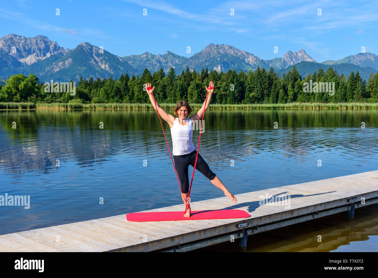 Femme faisant des exercices de Pilates sur un débarcadère dans contreforts des Alpes bavaroises près de Füssen. Banque D'Images