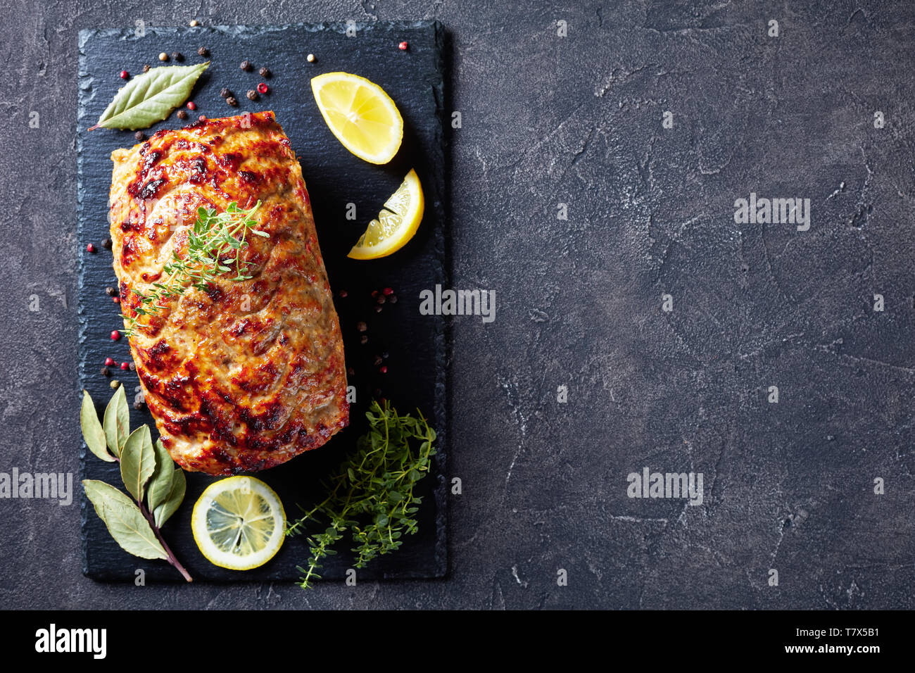 Pain de viande de poulet cuit sur une plaque en ardoise avec les tranches de citron et thym frais sur une table, vue de dessus, télévision lay, copy space Banque D'Images