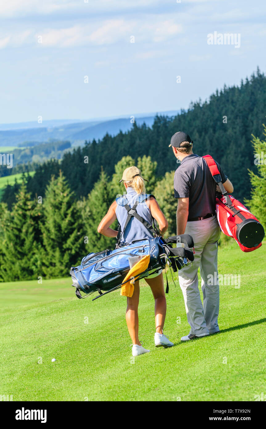 Couple playing golf, sur la voie sur fairway Banque D'Images
