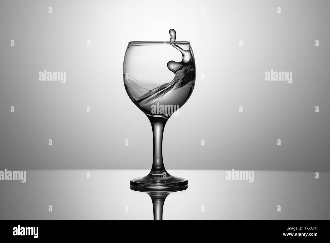 Splash d'eau claire dans un verre sur un fond de verre d'une réflexion Banque D'Images