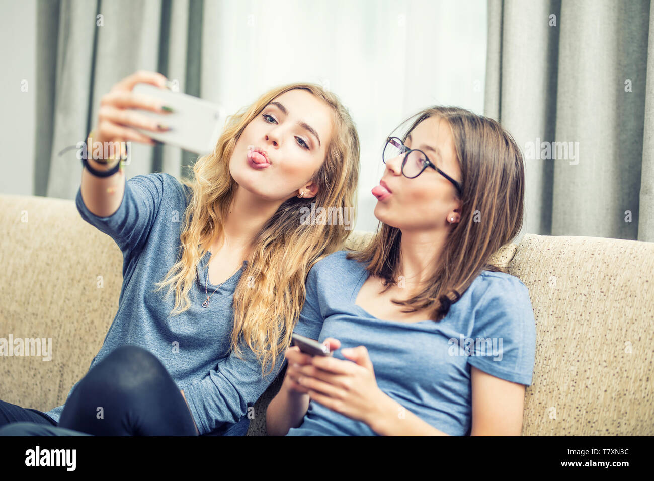 Deux adolescentes sourire et prendre un ensemble selfies. Ils font des grimaces de leur langue maternelle. Banque D'Images