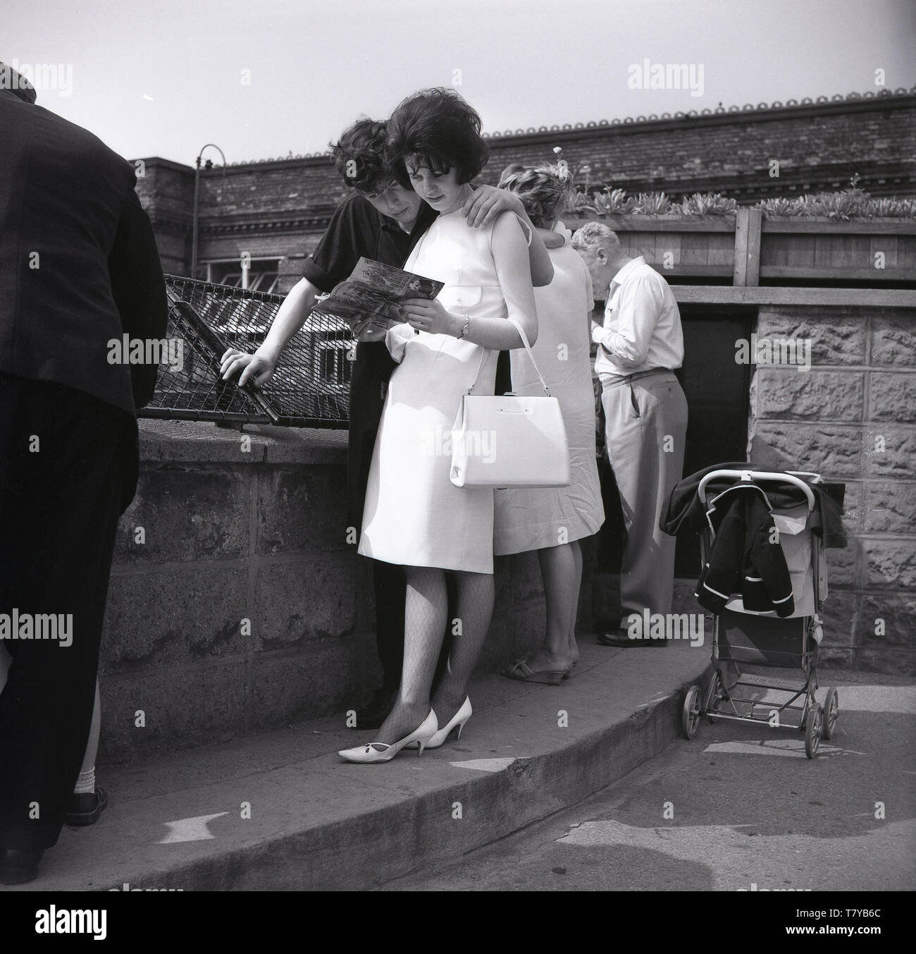 Années 1960, historiques, young couple visiter le Zoo de Londo étroitement à la recherche à l'article le guide du visiteur, Londres, Angleterre. Banque D'Images