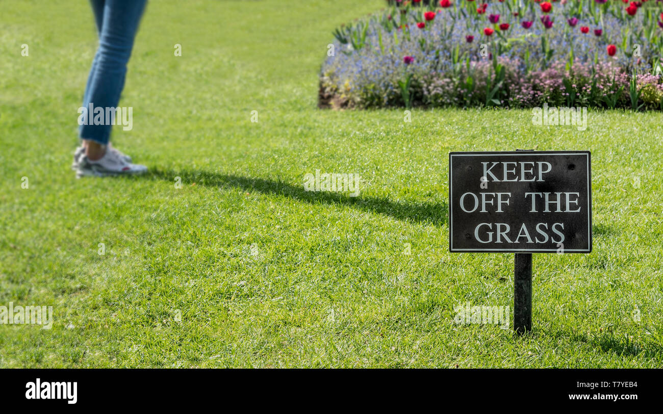 Ne pas marcher sur l'herbe signe avec pieds en arrière-plan sur l'herbe Banque D'Images