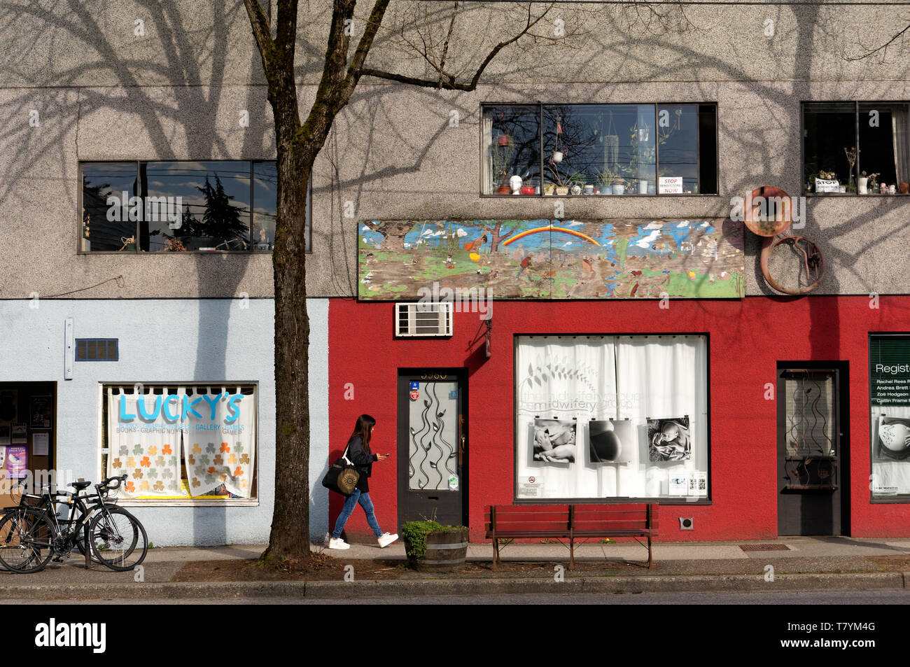 Une jeune femme en passant devant les vitrines colorées sur Main Street, Vancouver, BC, Canada Banque D'Images