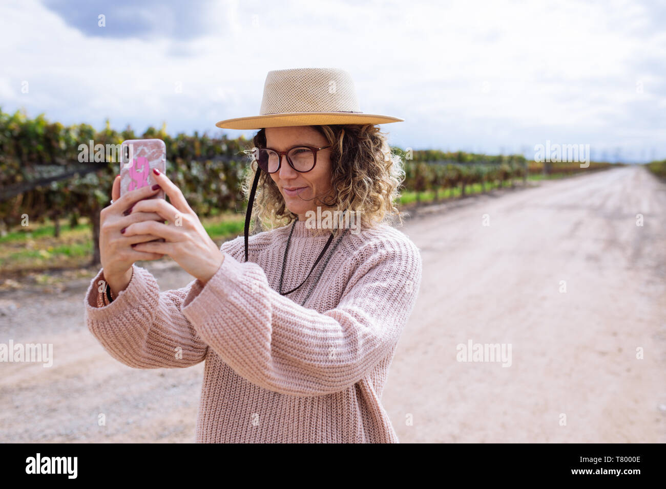 Femme prise d'une photo ou avec un chapeau selfies parmi la vigne dans la région de Bodega Septima Winery, Agrelo, Lujan de Cuyo, Mendoza, Argentine Banque D'Images