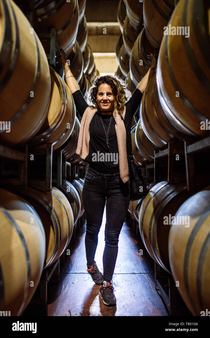 Caucasian woman touching barriques dans Bodega Septima, Agrelo, Lujan de Cuyo, Mendoza, Argentine Banque D'Images