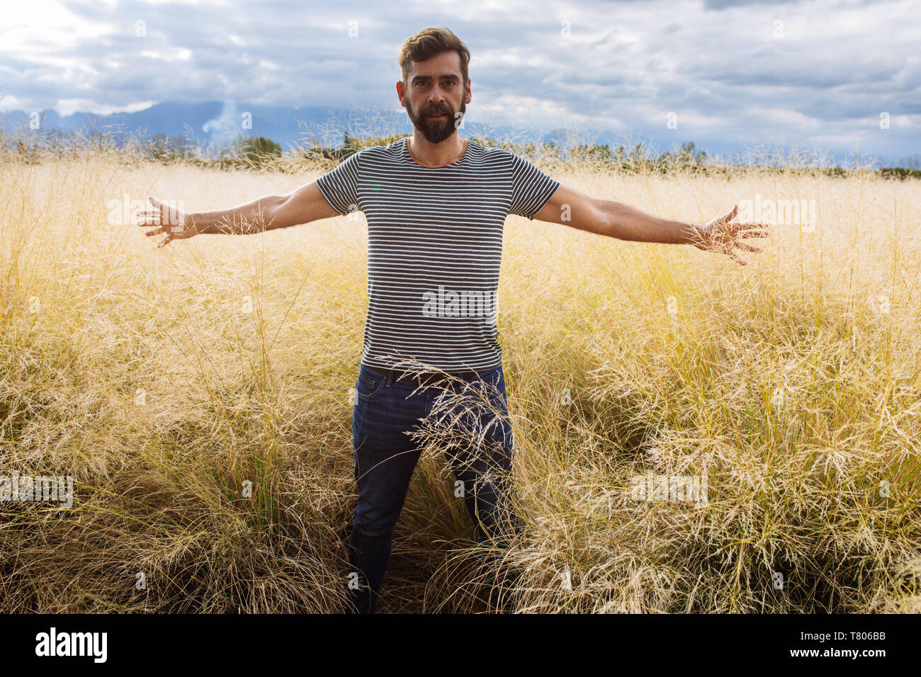 L'homme dans sa fin des années trente la mi-mi quarantaine, posant à bras ouverts dans un champ d'herbe jaune dans Bodega Septima Winery à Mendoza, Argentine Banque D'Images