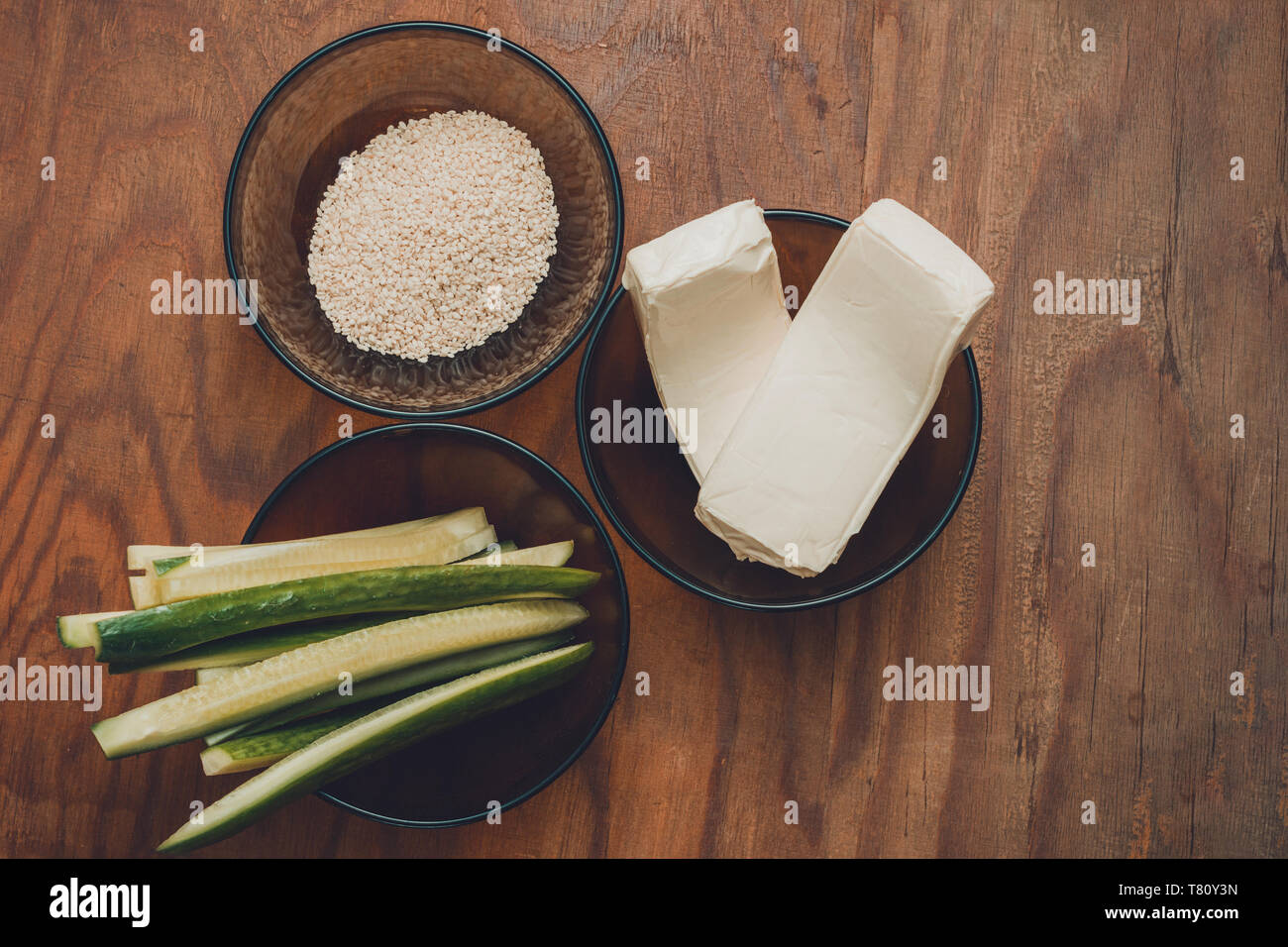 Une partie des ingrédients pour la préparation des sushis dans les assiettes sur la table, à savoir le riz, de fromage fondu, de concombres et de bâtonnets de crabe 2019 Banque D'Images
