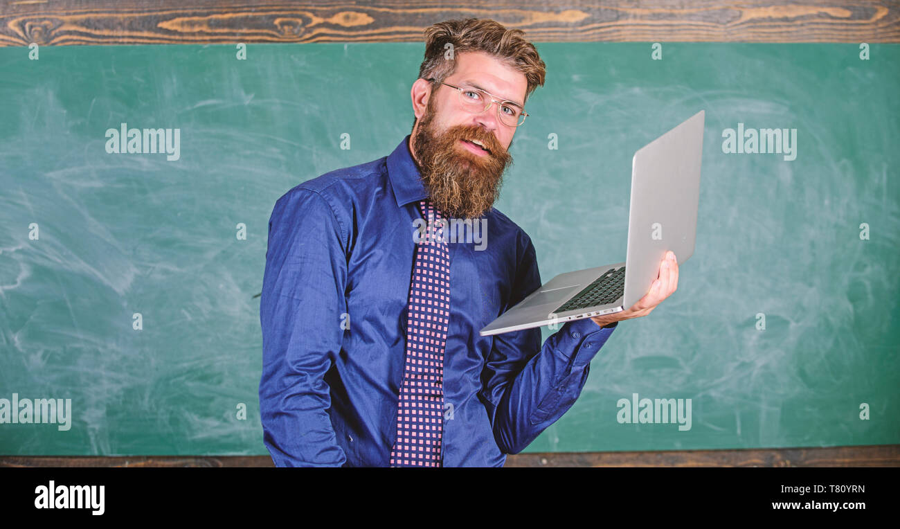 Professeur Hipster portent des lunettes et cravate est titulaire d'ordinateur portable Internet surf. Concept de formation à distance. Homme barbu enseignant avec ordinateur portable moderne tableau internet surf arrière-plan. Surfer sur internet. Banque D'Images
