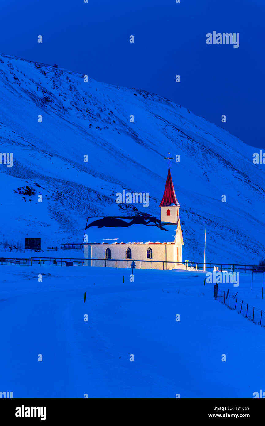 À l'aube de l'église illuminée contre montagnes couvertes de neige, hiver, près de Vik, le sud de l'Islande, Islande, régions polaires Banque D'Images