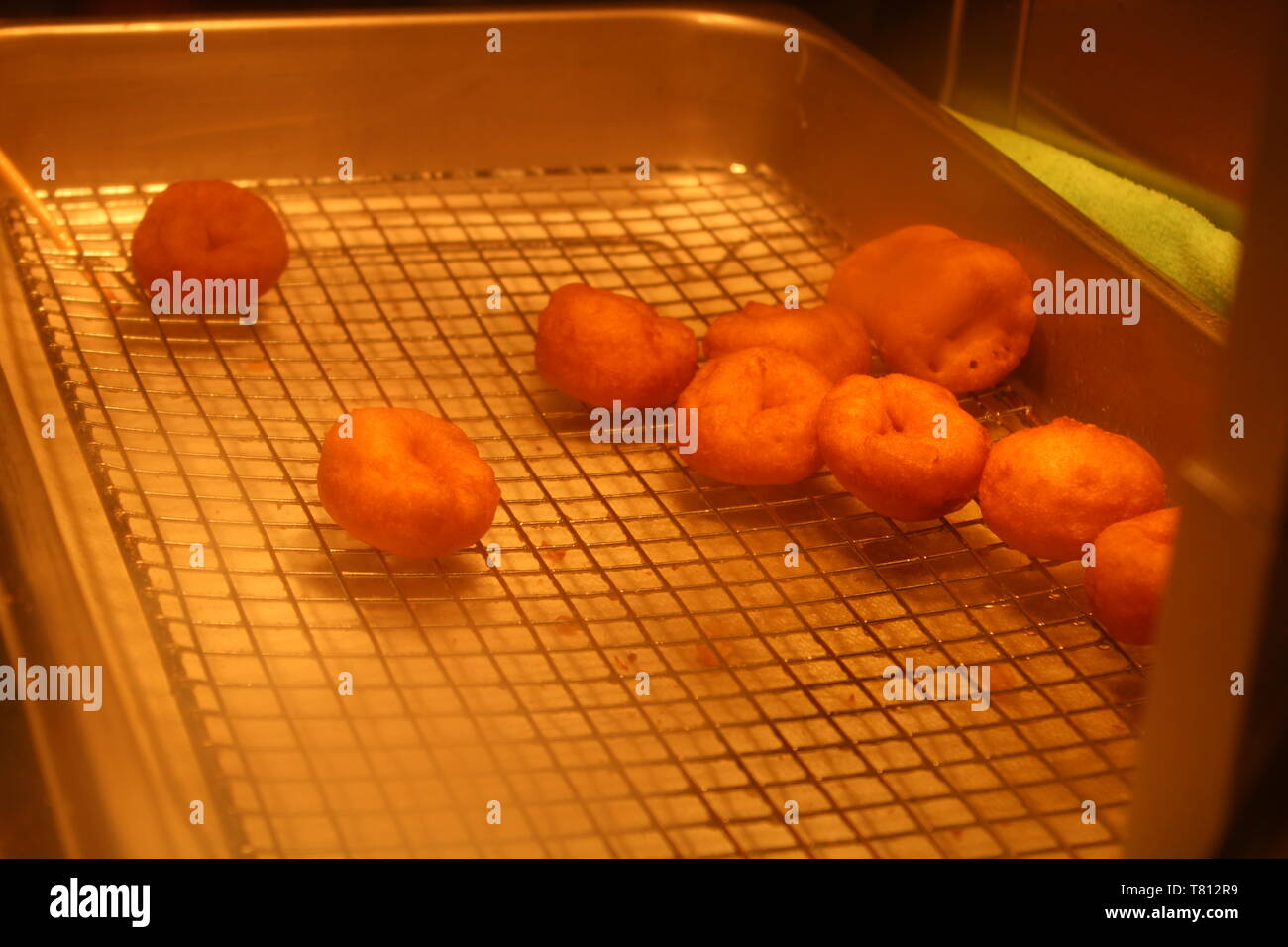 Newark DE/ USA 30/04/2019 : beignets frais sur un circuit de refroidissement en acier inoxydable de grade alimentaire allant au four pour qu'ils puissent être décoré avec du glaçage et saupoudrer de chocolat Banque D'Images
