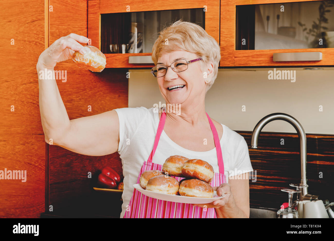 Young woman showing her des donut dans la cuisine. Banque D'Images