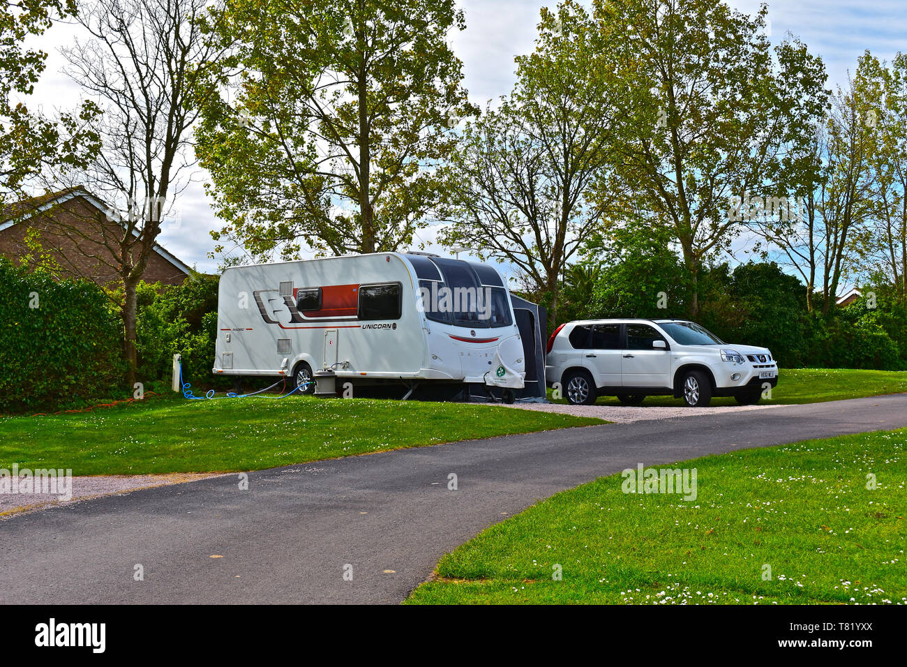 Voiture et caravane moderne tenue sur un terrain entièrement viabilisés à Beverley Park Holiday Park à Paignton, Devon. Contexte d'arbres entrée en feuille. Banque D'Images