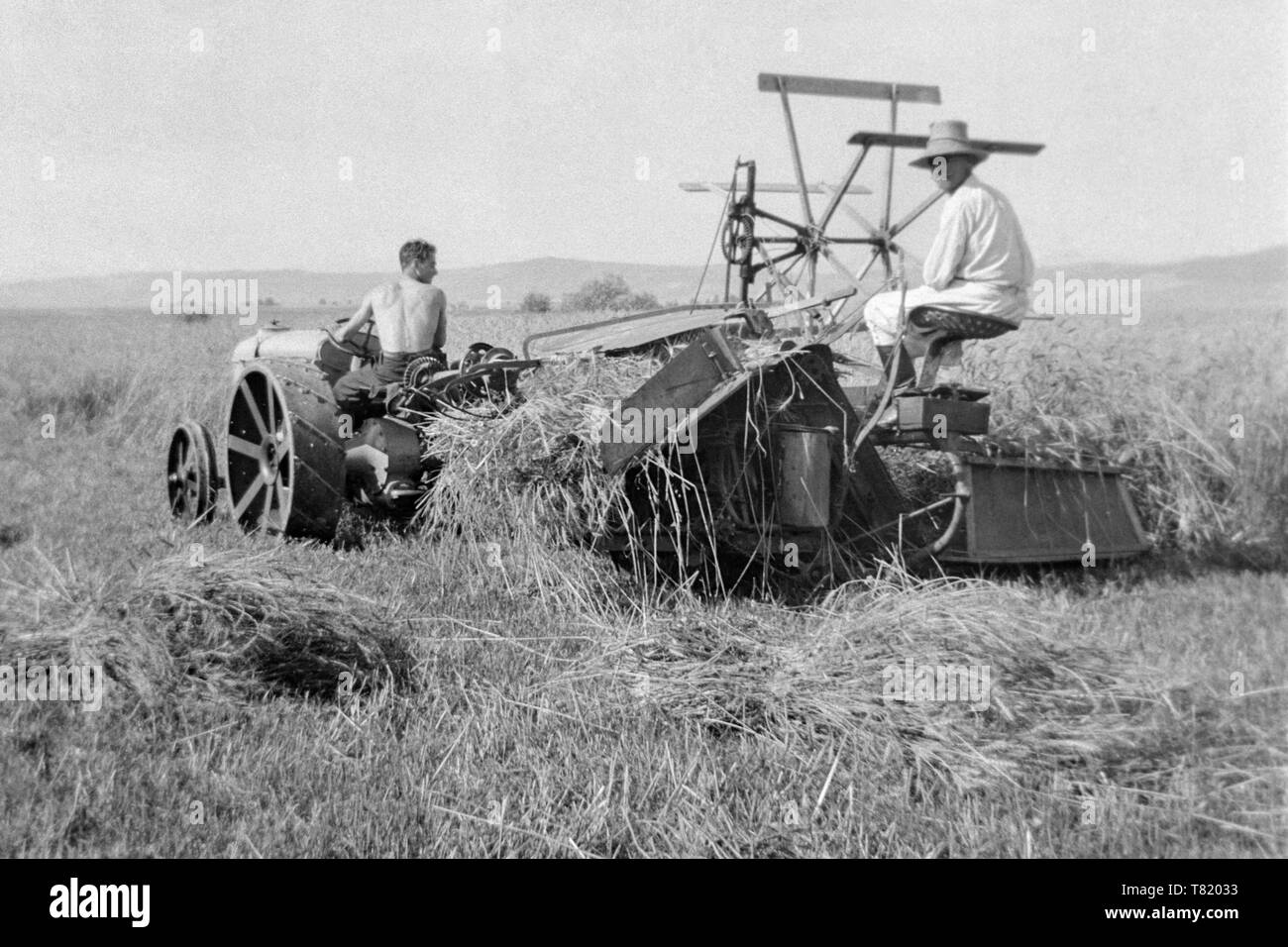 Deux hommes à l'aide d'un vieux tracteur et faucheuse rotative machine au moment de la récolte 1930 Hongrie Banque D'Images