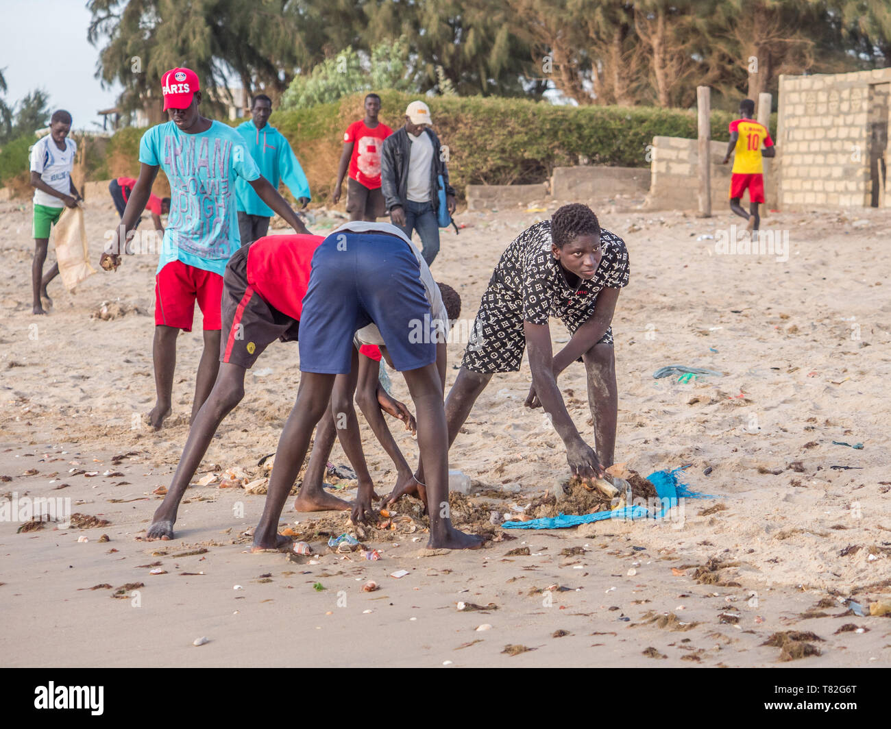 Le Sénégal, l'Afrique - le 26 janvier 2019 : les jeunes garçons africains sont le nettoyage de la plage de la pollution afin de jouer au football. Concept de la pollution. Fisher colorés Banque D'Images