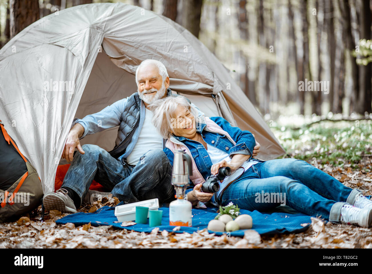 Joli couple ensemble au camping, un pique-nique sur un plaid près de la tente dans la forêt Banque D'Images