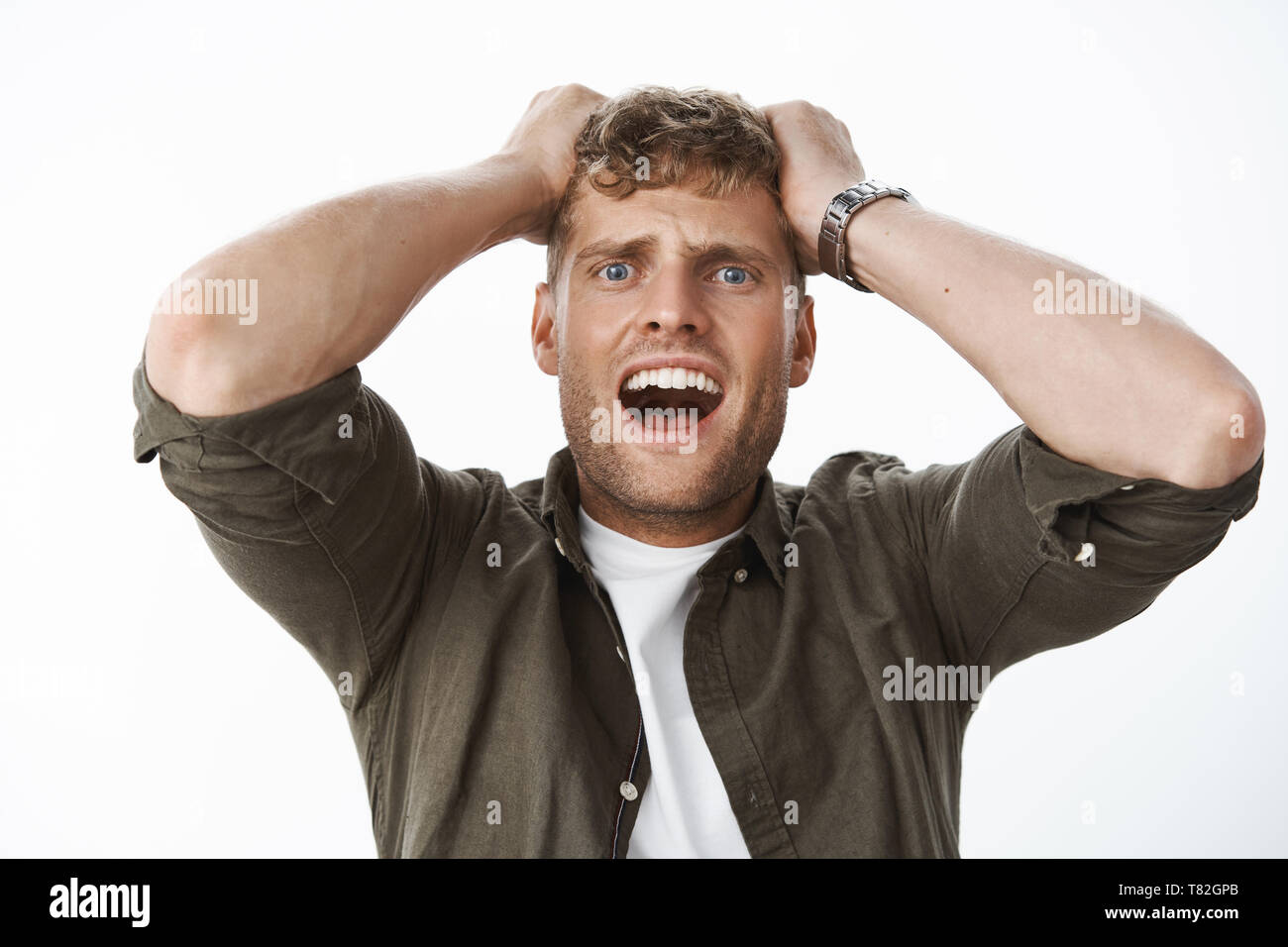 Choc intense guy dans la stupeur, les yeux bleus et les cheveux clairs  tenant les mains sur la tête en criant, hurlant de panique, panique,  stupéfait et permanent Photo Stock - Alamy