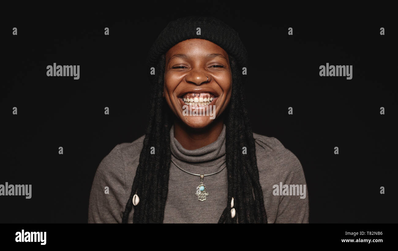 Portrait de femme africaine à avoir de longues dreadlocks avec un grand sourire. Pgortrait d'une femme heureuse isolé sur fond noir. Banque D'Images