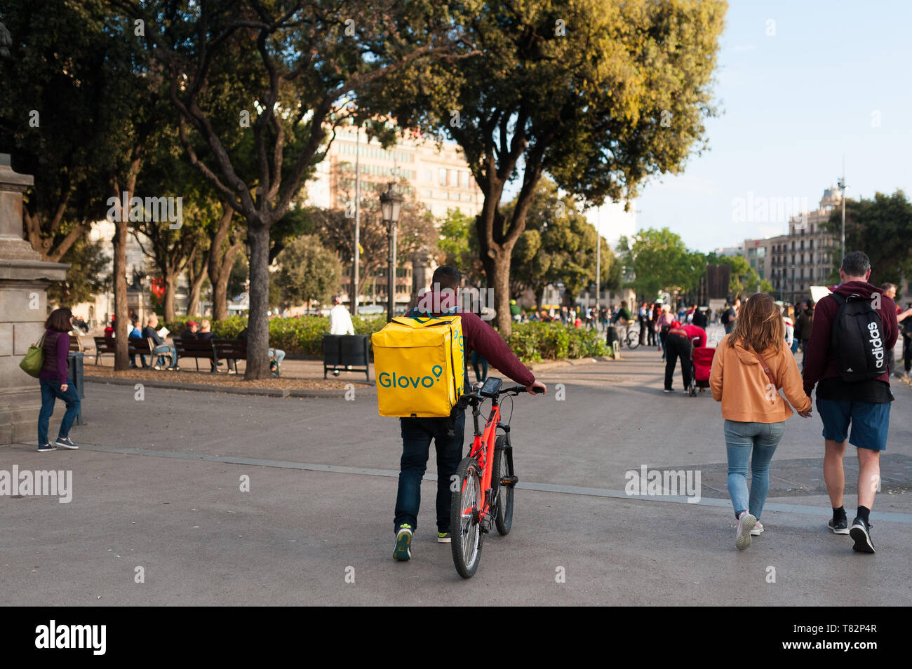 Bologne, Italie - 13 avril 2019 : jeune garçon glovo rider faire livraison sur son vélo travaillant dans la soi-disant économie concert place principale de Barcelone Banque D'Images