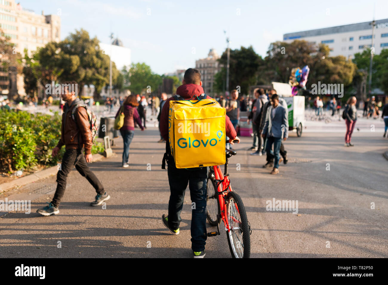 Bologne, Italie - 13 avril 2019 : jeune garçon glovo rider faire livraison sur son vélo travaillant dans la soi-disant économie concert place principale de Barcelone Banque D'Images