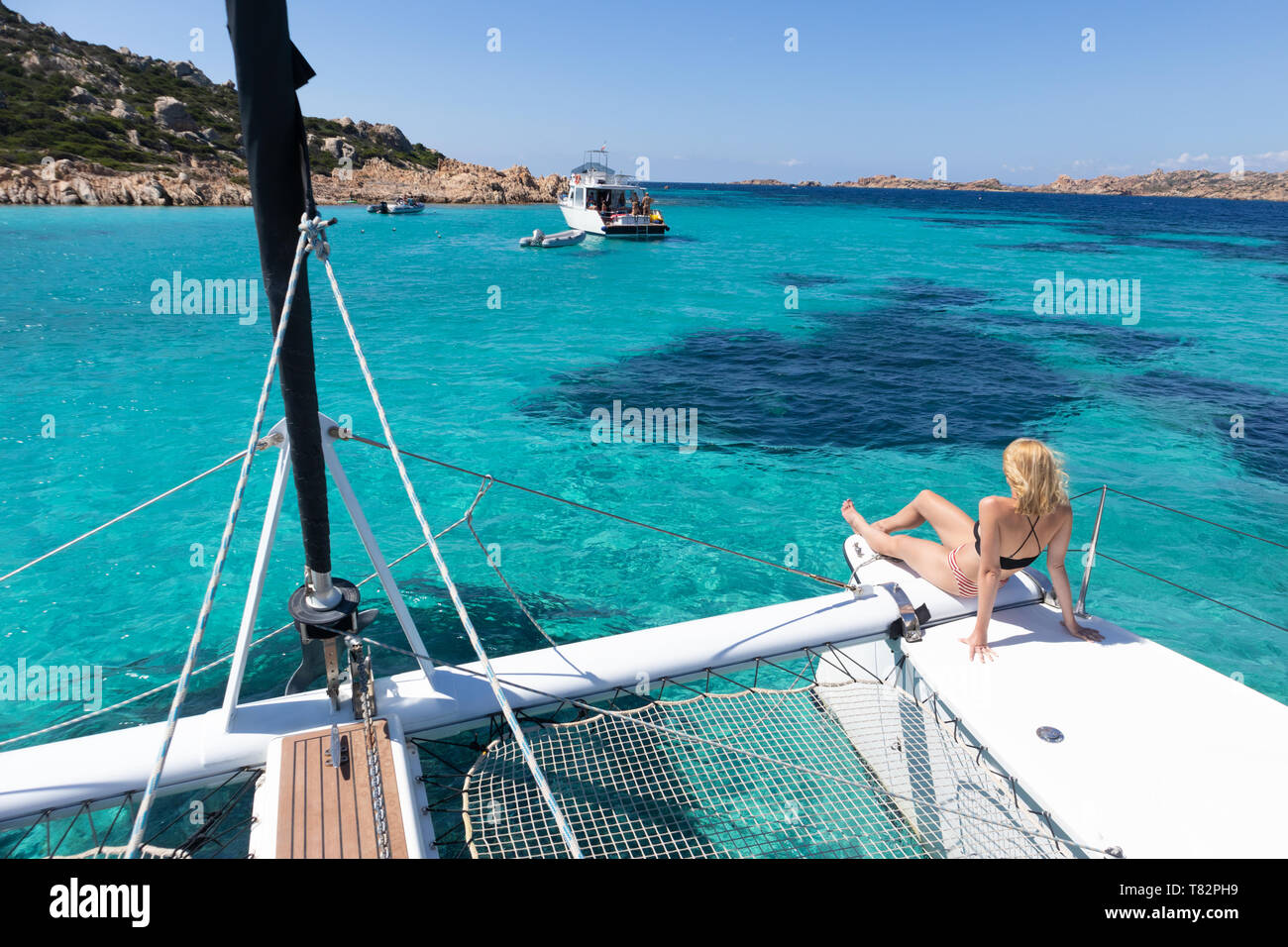 Femme se détendre sur une croisière d'été, assis sur un catamaran de luxe près de la plage de sable blanc sur l'île de Spargi dans Maddalena Banque D'Images