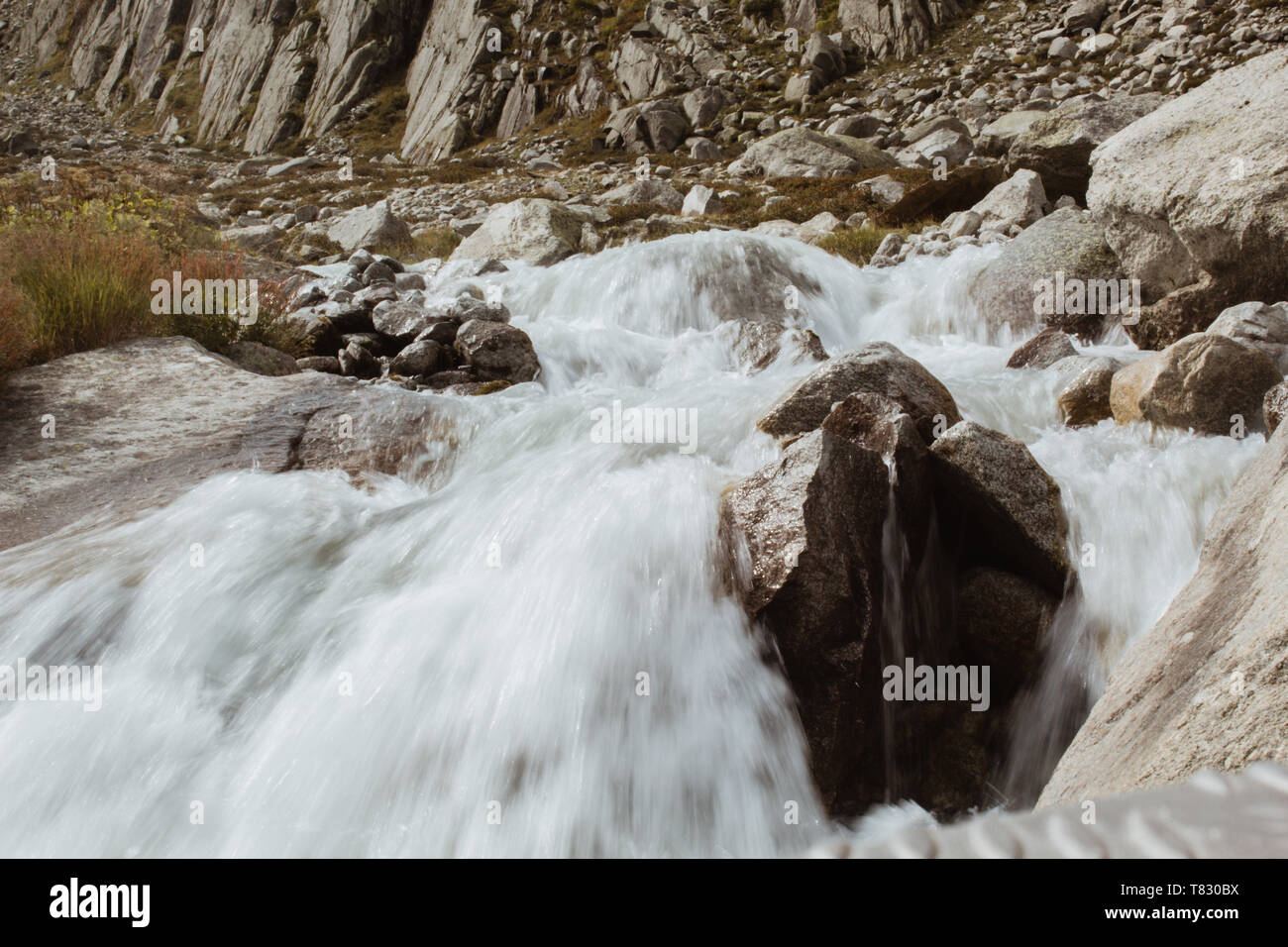 L'eau froide d'une rivière de montagne s'écoule entre l'été des pierres sur un fond de montagnes en suisse Banque D'Images