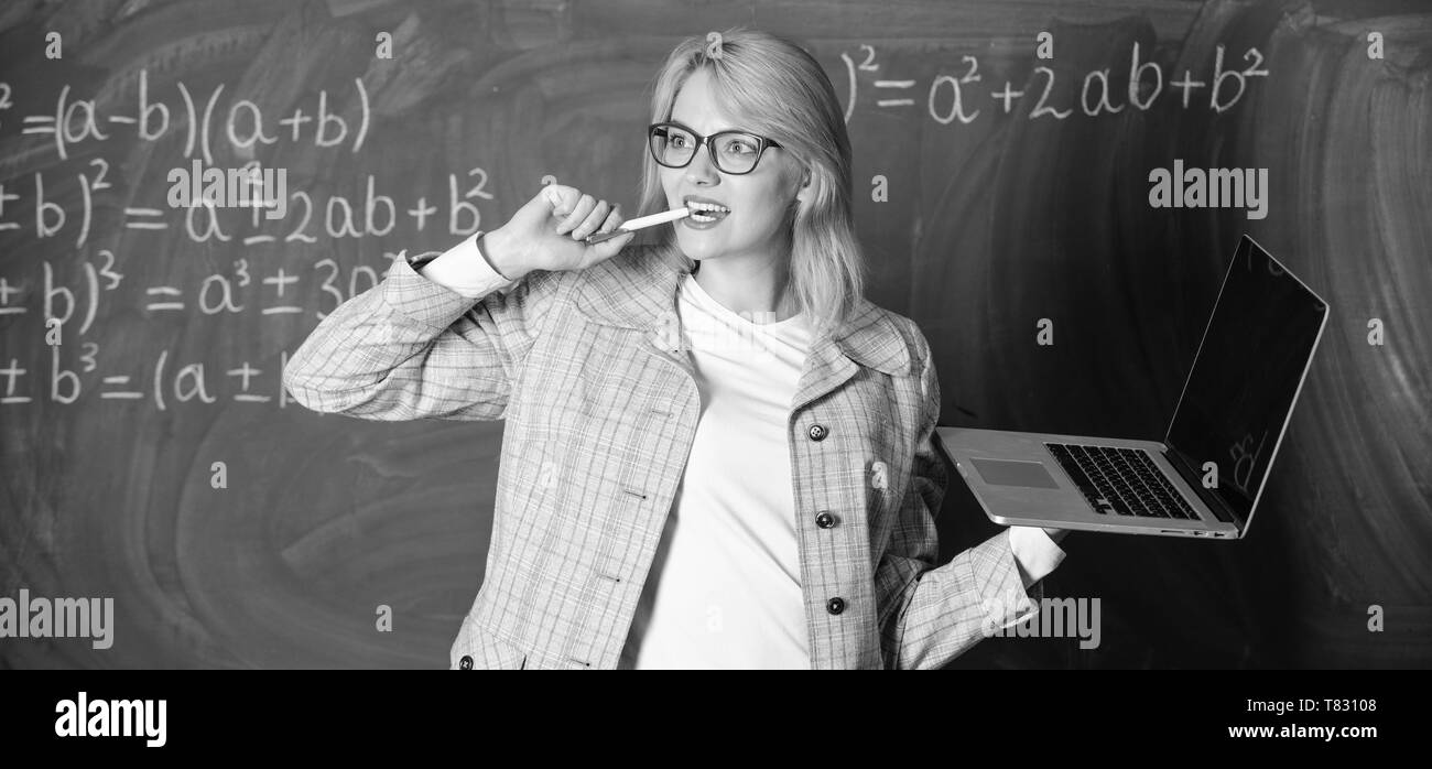 Enseignante portent des lunettes est titulaire d'ordinateur portable Internet surf. Dame intelligente smart éducateur avec ordinateur portable moderne tableau internet surf arrière-plan. Les technologies numériques concept. Idée sur son esprit. Banque D'Images