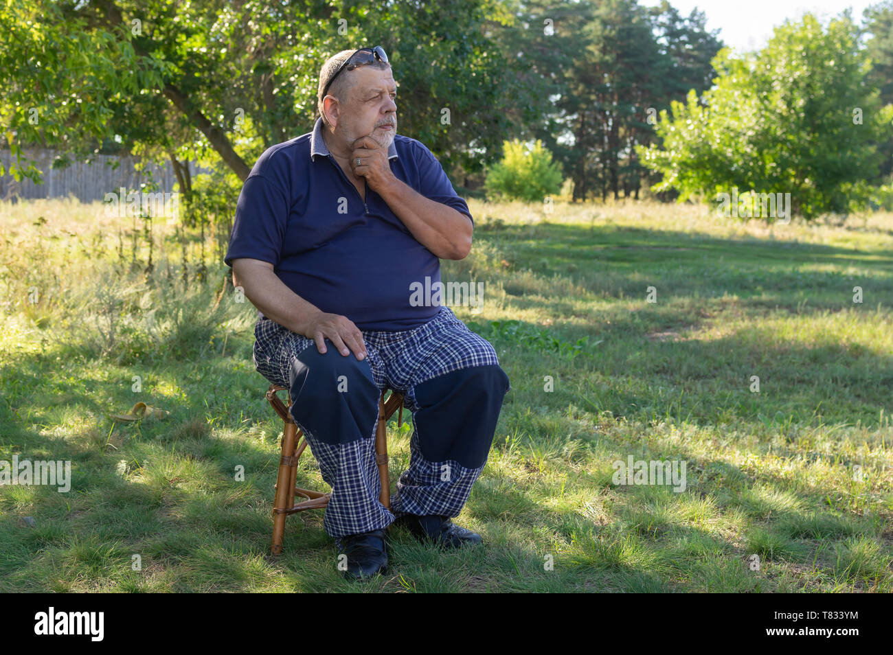 Belle piscine extérieure, portrait de l'Ukrainien happy homme assis sur un tabouret dans le jardin d'été Banque D'Images