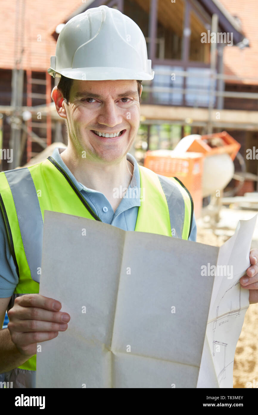 Portrait de travailleur de la construction sur chantier Looking At House Plans Banque D'Images