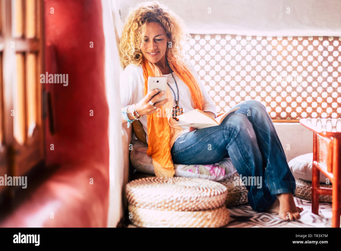 La mode à la mode belle jeune femme les gens à la maison assis et l'utilisation mobile phone at home - vêtements de style hippie et maisons colorées - femelle et techno Banque D'Images