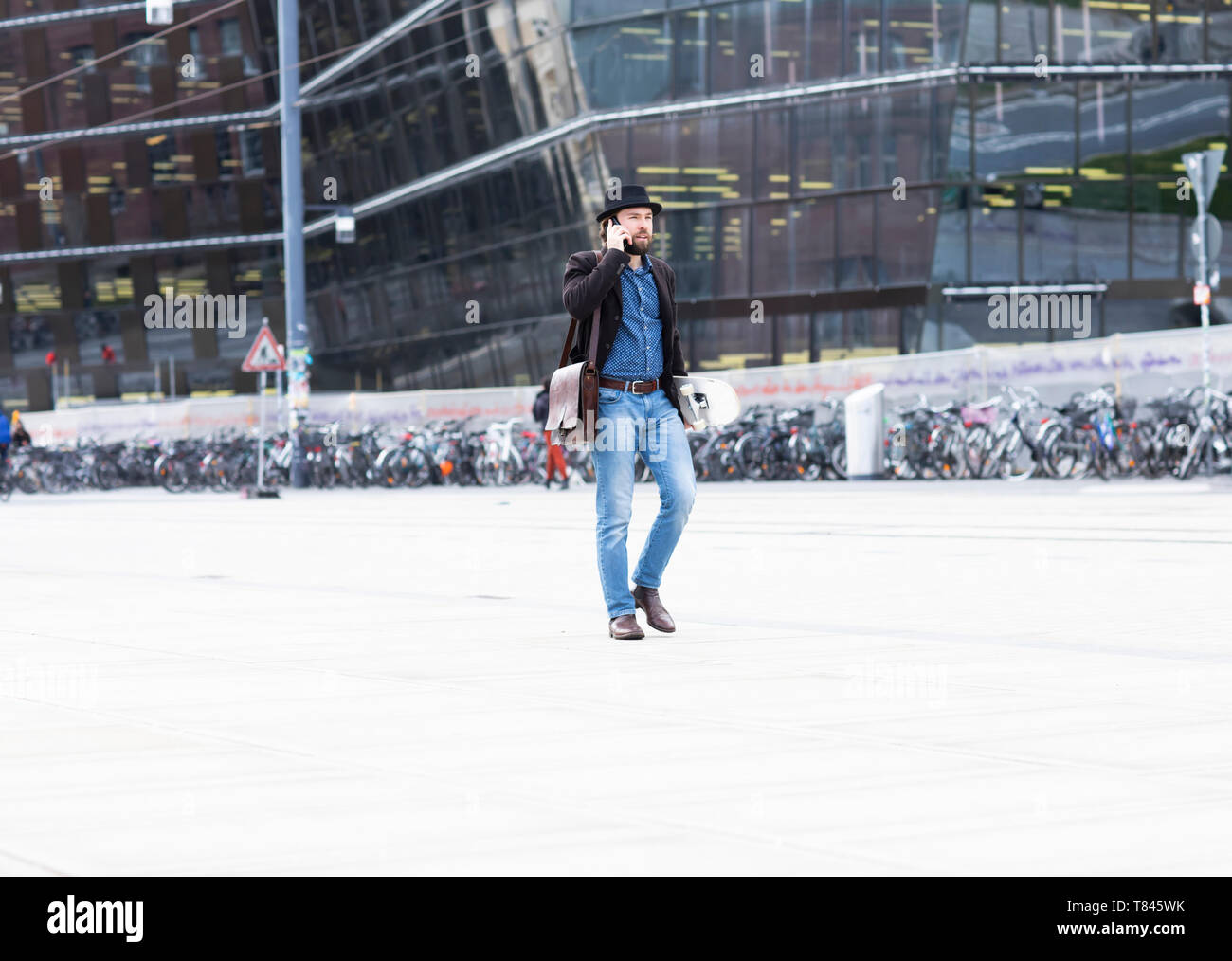 Skateboarder mâle flânant dans la ville faisant appel smartphone, Freiburg, Baden-Wurttemberg, Allemagne Banque D'Images