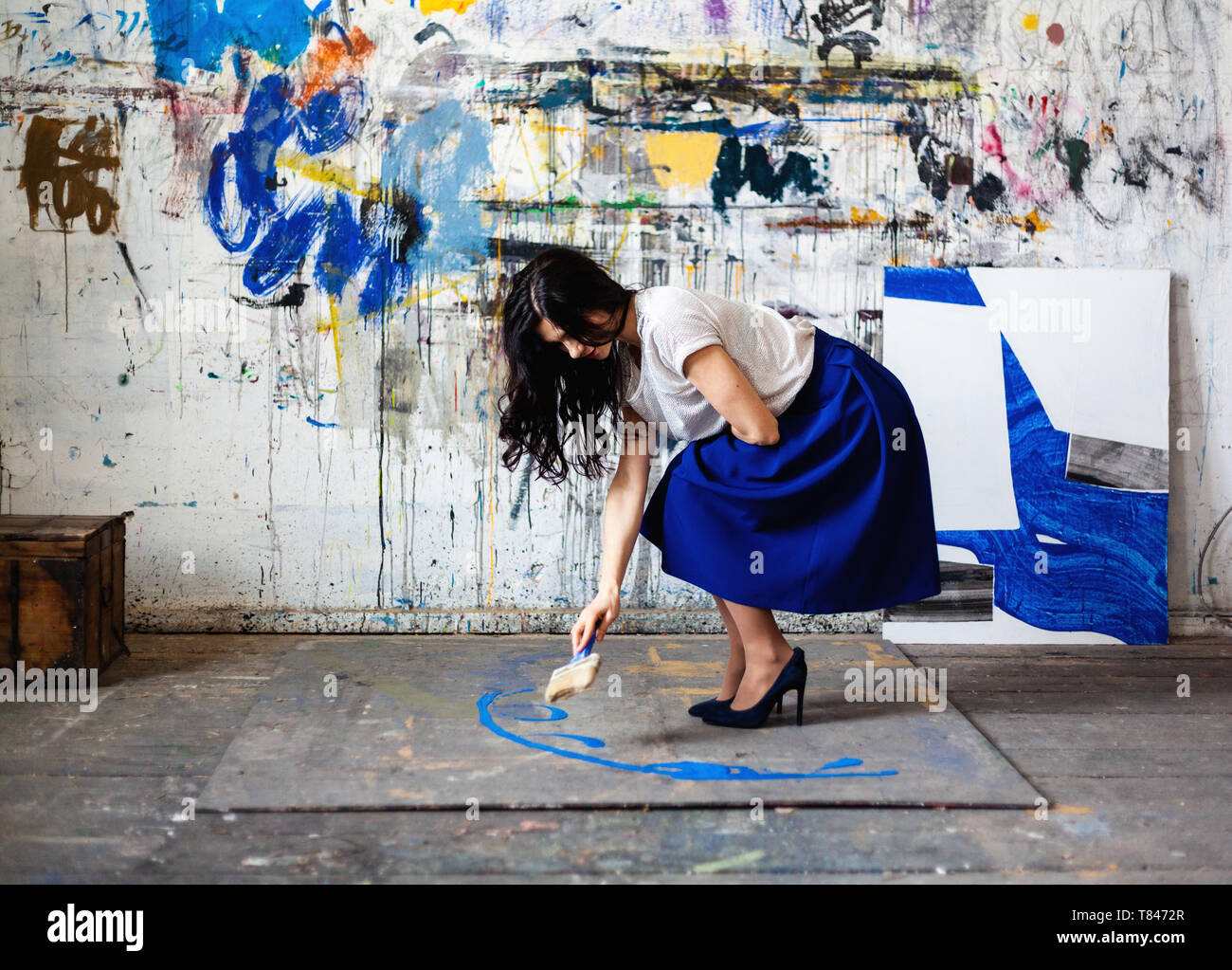 Femme peinture sur sol en face du mur de graffiti Banque D'Images