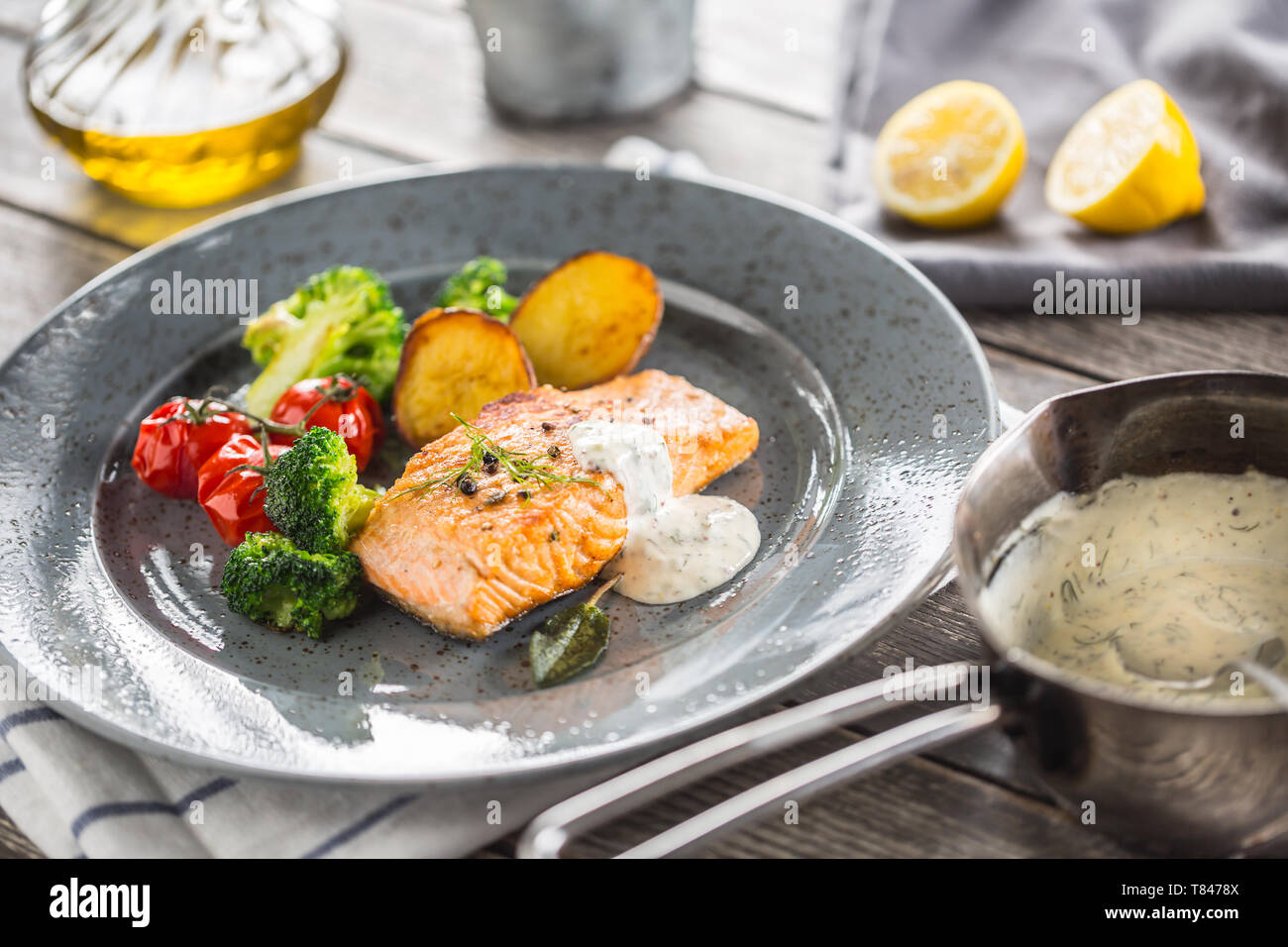Filet de saumon rôti tomates brocoli et pommes de terre frites avec sauce à la crème d'aneth Banque D'Images