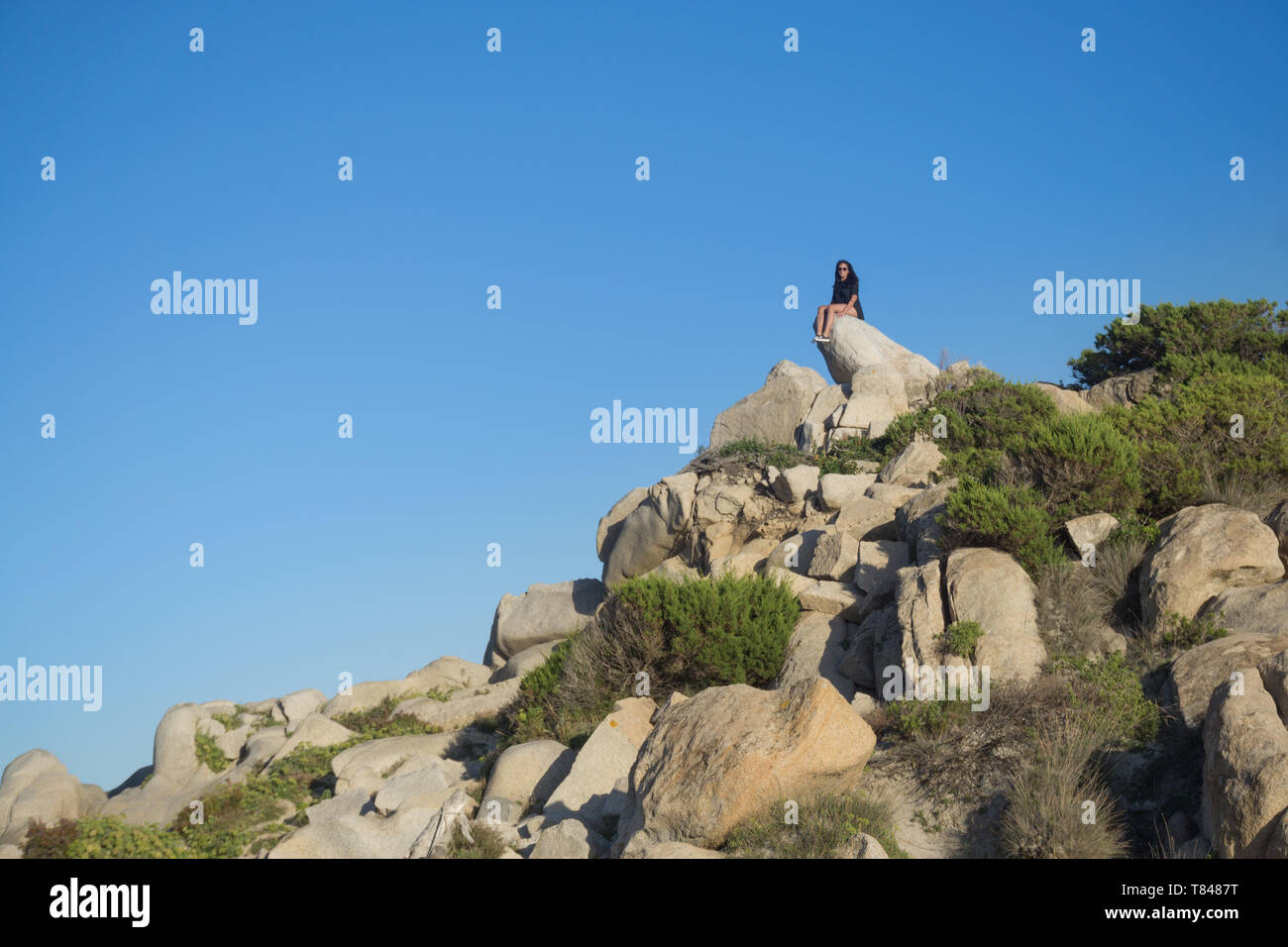 Woman sitting on rock, Villasimius, Sardaigne, Italie Banque D'Images